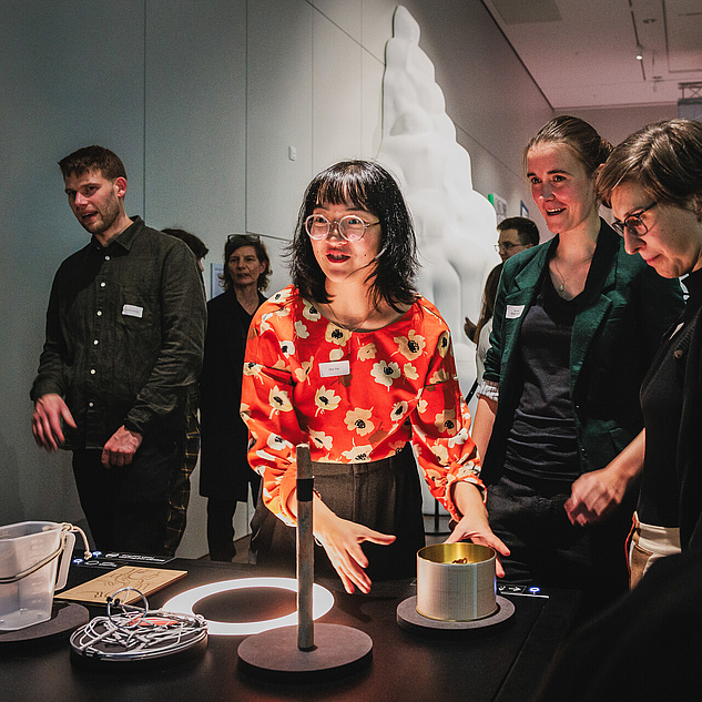 OnWater-Ausstellung des Humboldt Labors Eine Frau erklärt Besucher*innen während der Ausstellung ein Ausstellungstück und seine Funktionsweise.